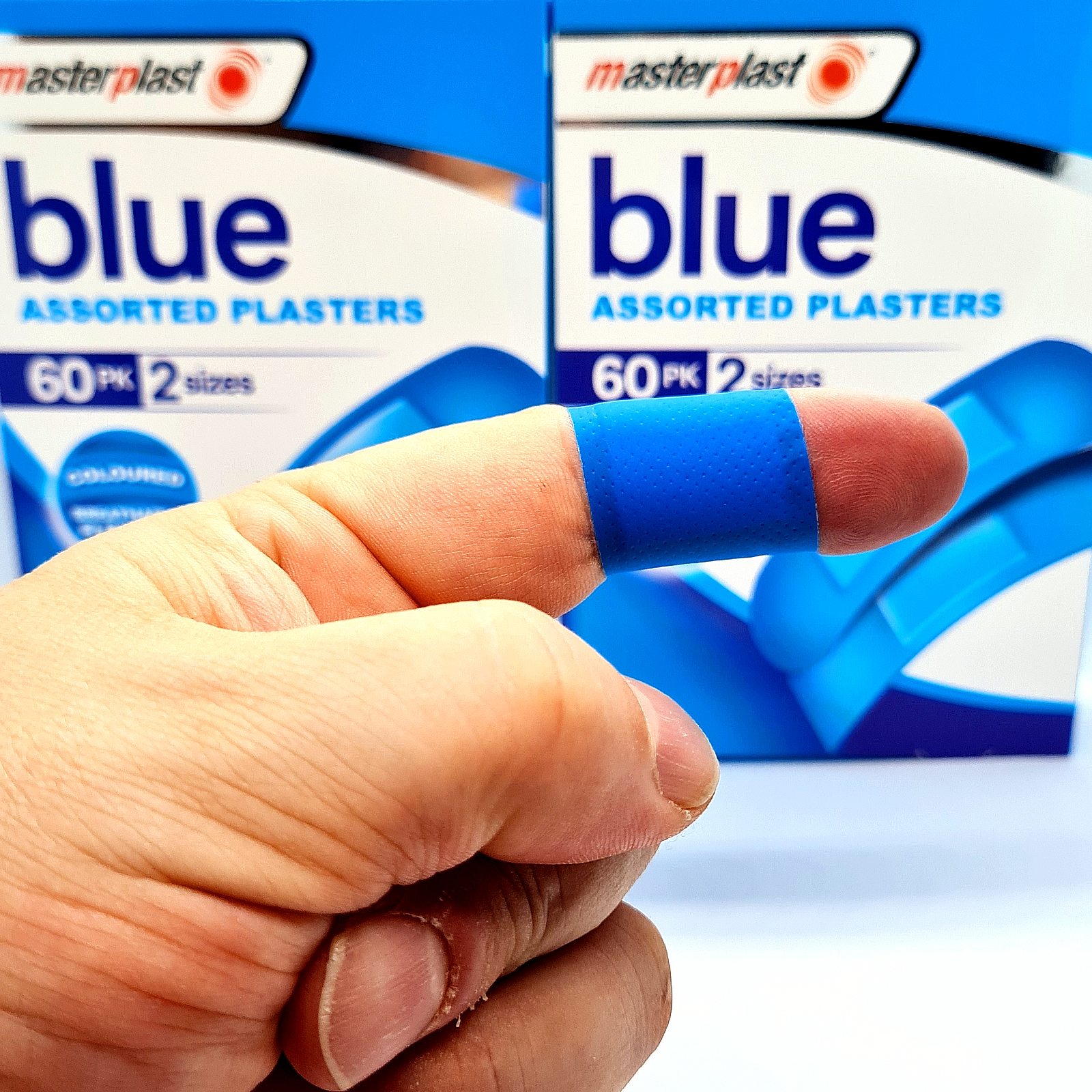 Hand wearing a blue plaster with Masterplast packaging in the background