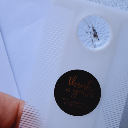Black round sticker with 'thank you' text on a white background