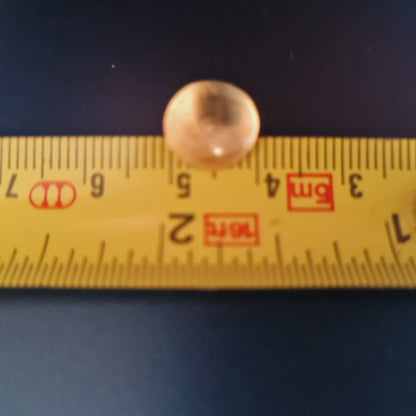 Measuring tape with a round object on a dark background